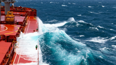 Waves crashing against cargo ship at sea